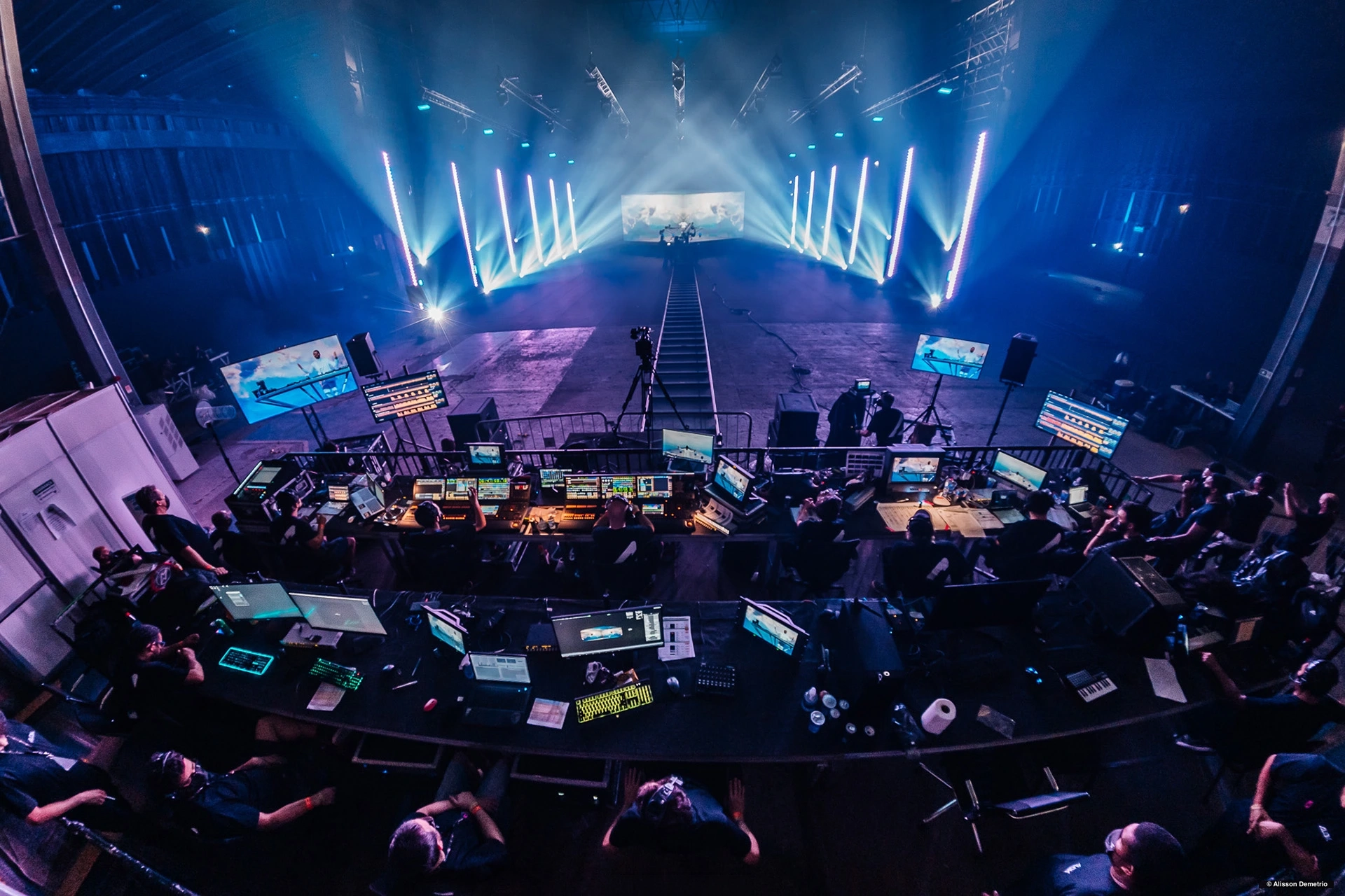 A wide view of the Alok Alive production, with the control desks in the foreground and the illuminated stage beyond the camera track.